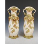 A pair of Art Nouveau Royal Dux porcelain twin handled vases of organic form, moulded with fruit and
