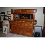 VICTORIAN CARVED OAK CHIFFONIER WITH UPRIGHT MIRRORED BACK, THREE CARVED PANELLED DOORS AND THREE