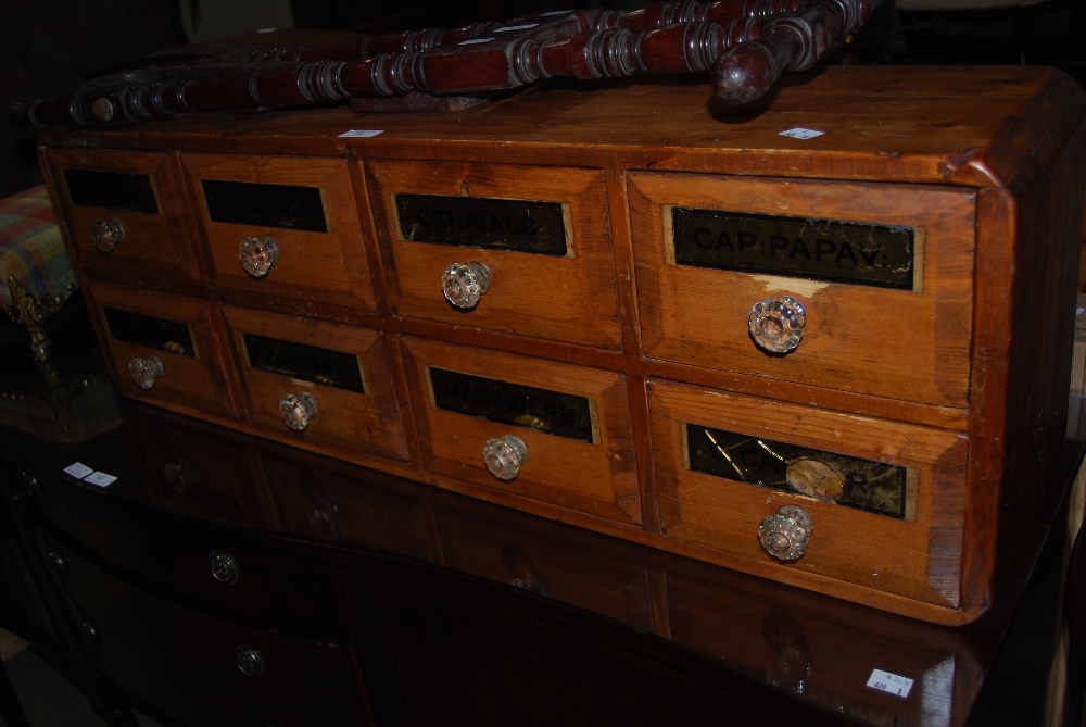 BANK OF EIGHT STAINED PINE CHEMISTS APOTHECARY DRAWERS WITH GLASS HANDLES