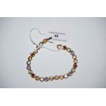 A 9CT GOLD MULTI COLOURED GEM SET ARTICULATED BRACELET