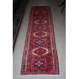 EASTERN PATTERNED RED GROUND RUNNER WITH GEOMETRIC DESIGN BORDER AND CENTRAL PANEL OF FOUR LARGE