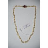 A SINGLE STRAND GRADUATED PEARL NECKLACE WITH 9CT GOLD CLASP, CENTRED WITH A FACET CUT AMETHYST