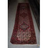 EASTERN PATTERNED RED GROUND RUNNER WITH GEOMETRIC DESIGN BORDER AND CENTRAL PANEL OF THREE LARGE