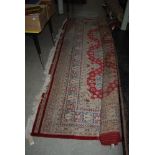 RED GROUND EASTERN PATTERNED CARPET WITH GEOMETRIC DESIGN BORDER AND LARGE CENTRAL PANEL OF