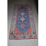 EASTERN PATTERNED RED GROUND RUG WITH GEOMETRIC DESIGN BORDER AND CENTRAL BLUE GROUND PANEL WITH