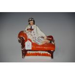 A 19TH CENTURY STAFFORDSHIRE FLAT BACK FIGURE OF A GIRL RECLINING ON A CHAISE LONGUE READING A