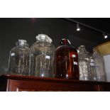 COLLECTION OF ASSORTED CLEAR GLASS DEMI JOHNS, TOGETHER WITH AN AMBER TINTED DEMI JOHN