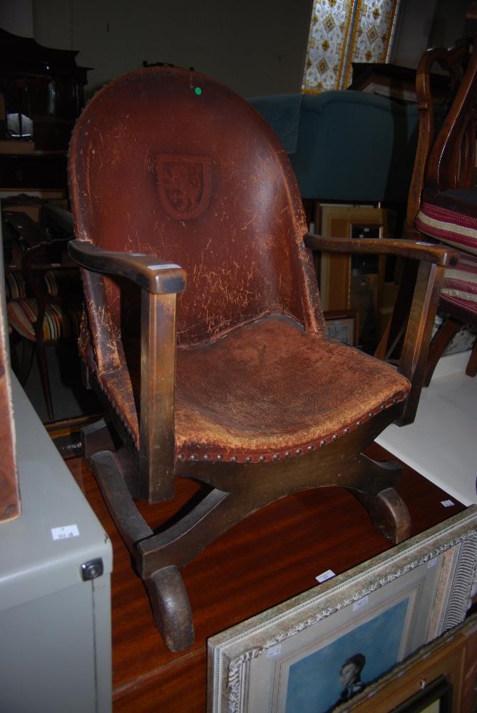 EARLY 20TH CENTURY STAINED BEECH AND LEATHER UPHOLSTERED TUB CHAIR WITH HERALDIC CREST OF LION