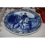 A ROYAL SPHINX DELFT POTTERY CHARGER DECORATED WITH MALE AND FEMALE IN CARRIAGE