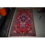 PERSIAN MADDER GROUND RUG CENTRED WITH LARGE BLUE GROUND FOLIATE MEDALLION