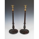 A pair of George III style mahogany and brass candlesticks, the brass urn shaped nozzles with