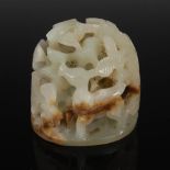 A Chinese celadon and russet jade boulder, carved and pierced with two deer and foliage, the base