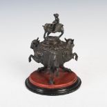 A 19th century bronze inkwell, cast with three rampant bulls divided by satyr masks, the