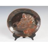 A Japanese bronzed spelter dish, Meiji Period, decorated in relief with seated figure with