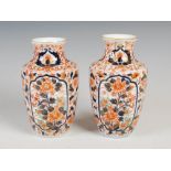 A pair of Japanese Imari porcelain vases, decorated with oval shaped panels of peony on a