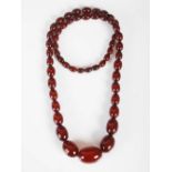 A red amber necklace, formed from fifty five graduated oval beads, 65.7 grams.