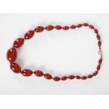 A red amber necklace, formed from twenty seven graduated oval beads, gross weight 46.3 grams.