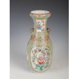A Chinese apple green ground famille rose vase, Qing Dynasty, decorated with oval shaped panels
