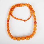 A graduated butterscotch amber necklace, formed from sixty three graduated oval shaped beads,