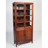 A Chinese dark wood two part display cabinet, late 19th/early 20th century, the upper part with