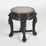 A Chinese dark wood urn stand, Qing Dynasty, the shaped circular top with a mottled red and white