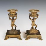 A pair of 19th century gilt bronze twin handled urns, supported on figural columns and square