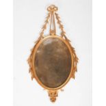 A Neo Classical style gilt wood wall mirror, the oval mirror plate suspended from ribbon tie and
