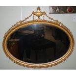 A late 19th/early 20th century gilt wood overmantel, the bevelled oval mirror plate within a gilt