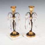 A pair of early 19th century bronze and gilt bronze candlesticks, the urn shaped nozzles raised on