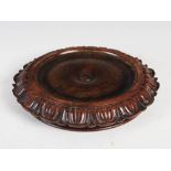 A Scottish Regency mahogany coaster by James Mein, Kelso, of circular form with foliate carved edge,