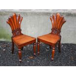 A pair of 19th century mahogany fan back hall chairs, the fan shaped backs carved with floral