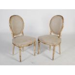 A pair of white painted beech wood side chairs in the French style, the oval upholstered backs and