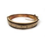 A 9ct gold bangle having an engraved and