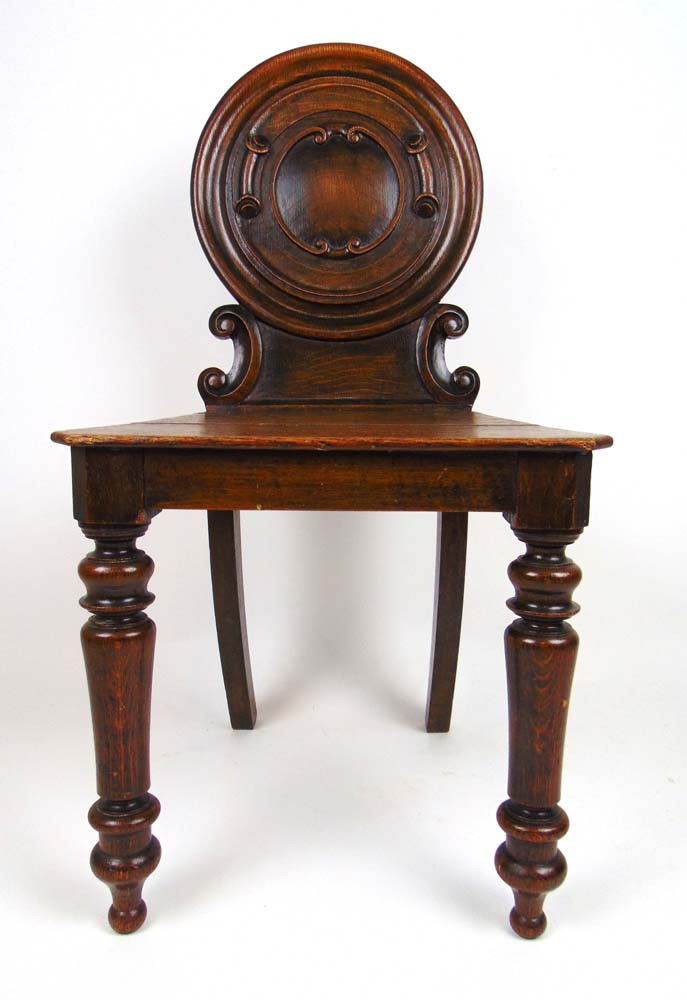 A 19th century oak hall chair, the circu