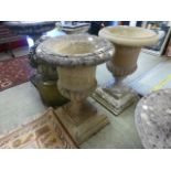 A pair of weathered pedestal planters on