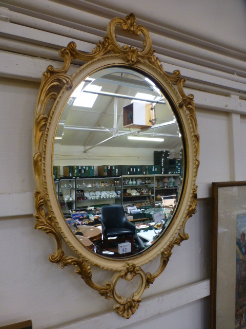 An ornate cream and gilt painted bevel g