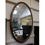 An oval oak framed bevel glass wall mirr