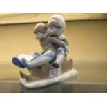 A Lladro figure of two children on a sle