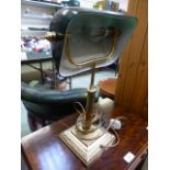 A brass desk lamp with a green glass sha