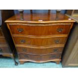 A yew veneered serpentine chest of four