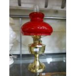 A brass bodied oil lamp having a red gla