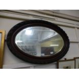 An oval bevel glass mirror with ornate f
