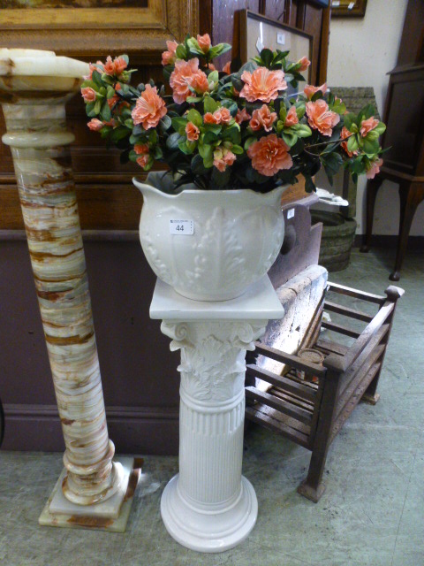 A white ceramic jardiniere stand with pl