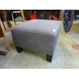 A modern grey upholstered foot stool
