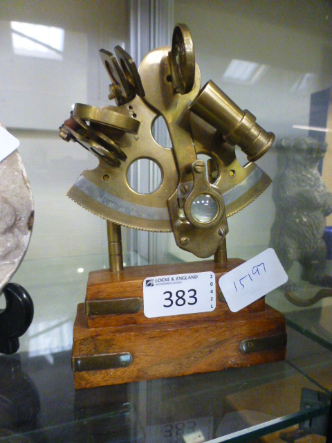 A small brass sextant on wooden stand