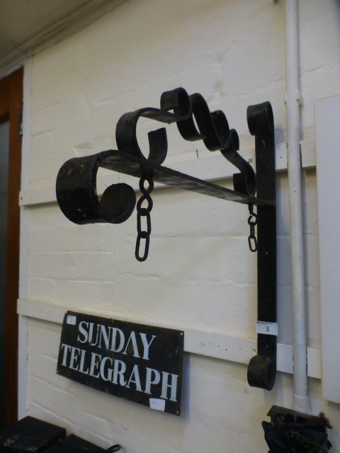 A wrought iron wall mounted sign hanging