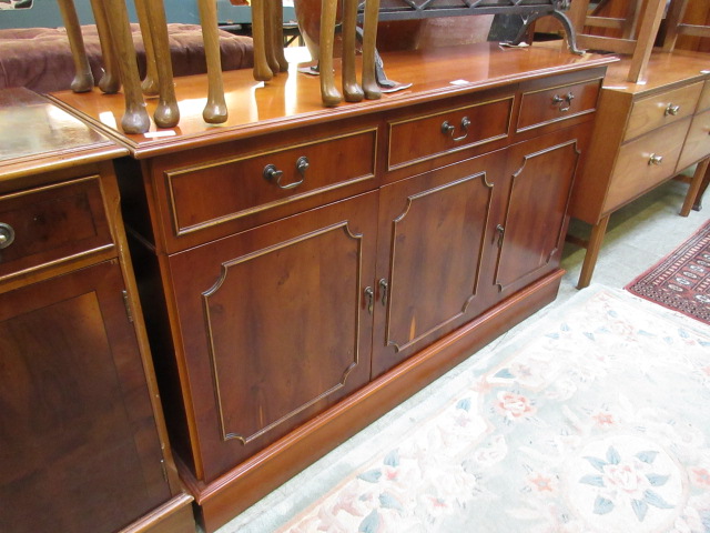 A reproduction yew sideboard having thre