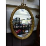 An ornate gilt framed oval mirror
