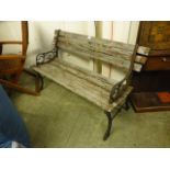 A weathered teak garden bench with cast