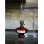 A late Victorian cranberry glass and brass oil lamp